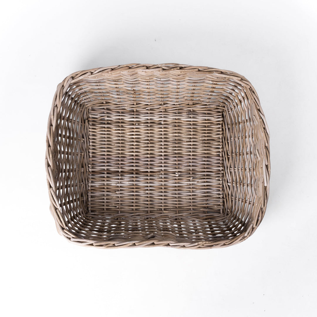 A classic wicker dog basket - a grewash rattan dog basket - woven with natural rattan canes, on a white background, viewed from above.