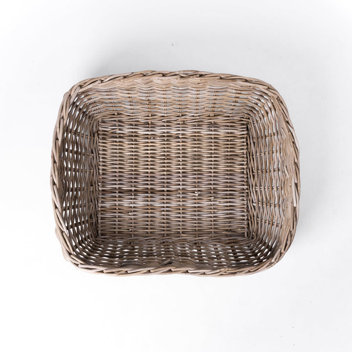 A classic wicker dog basket - a grewash rattan dog basket - woven with natural rattan canes, on a white background, viewed from above.