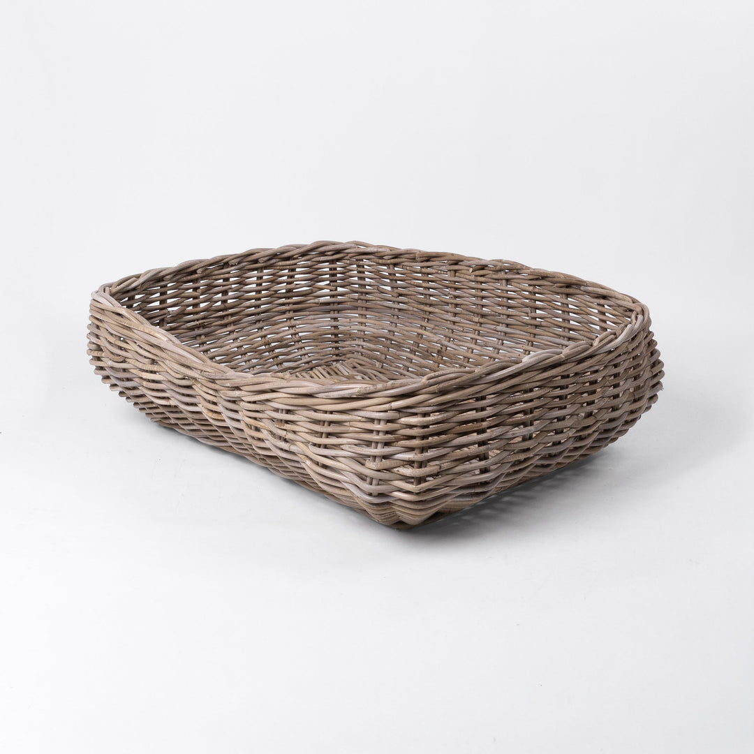 A classic wicker dog basket - a grewash rattan dog basket - woven with natural rattan canes, on a white background.