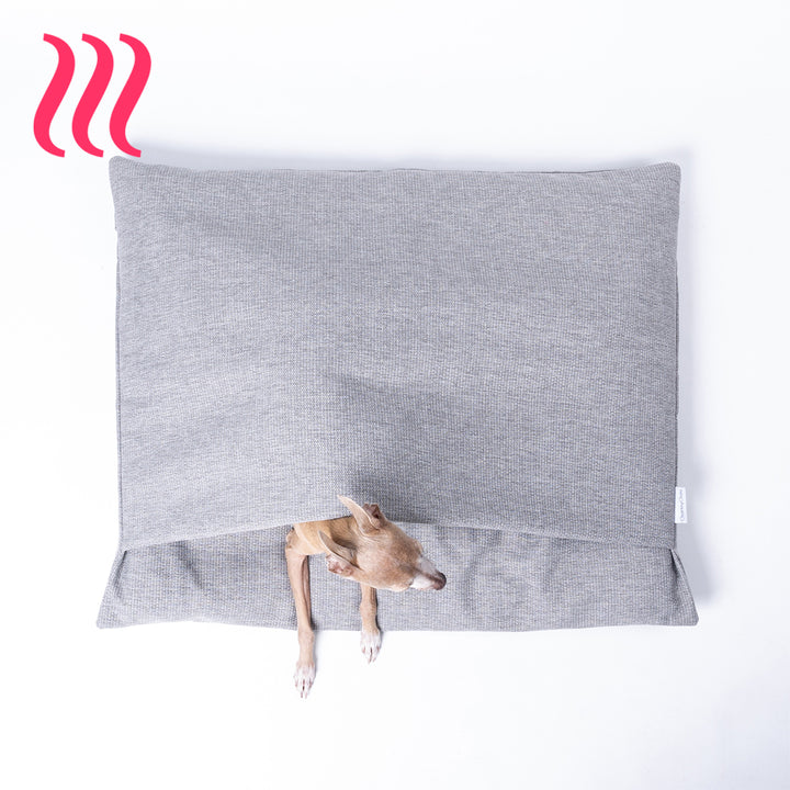 Italian Greyhound dog peeking out of a luxury sleeping bag style dog burrow bag by Charley Chau in a grey woven upholstery fabric with the Charley Chau brand label visible, on a white background.