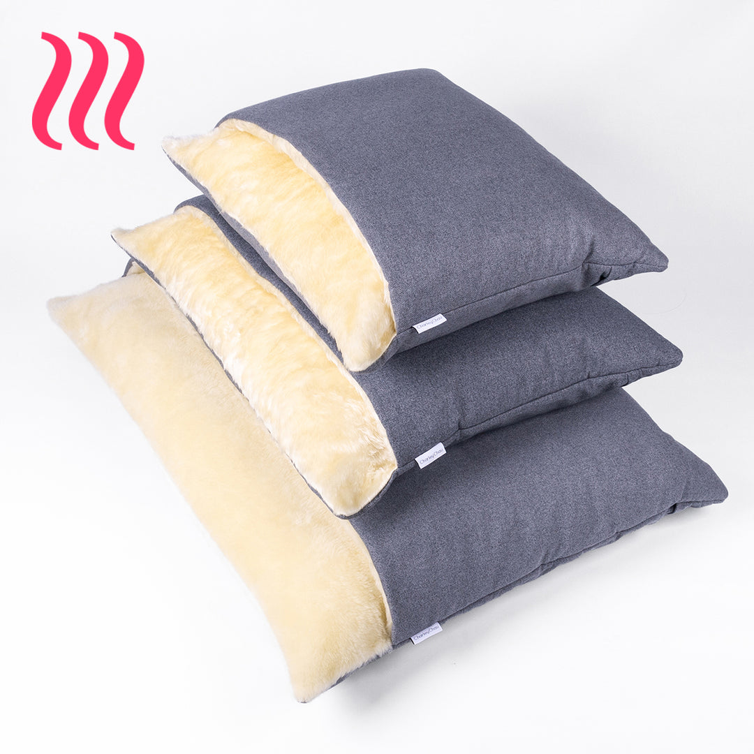 Three different size luxury Dog Snuggle Beds stacked up with outer covers in  dark grey and cream faux-fur on the inside of the beds, on a white background.