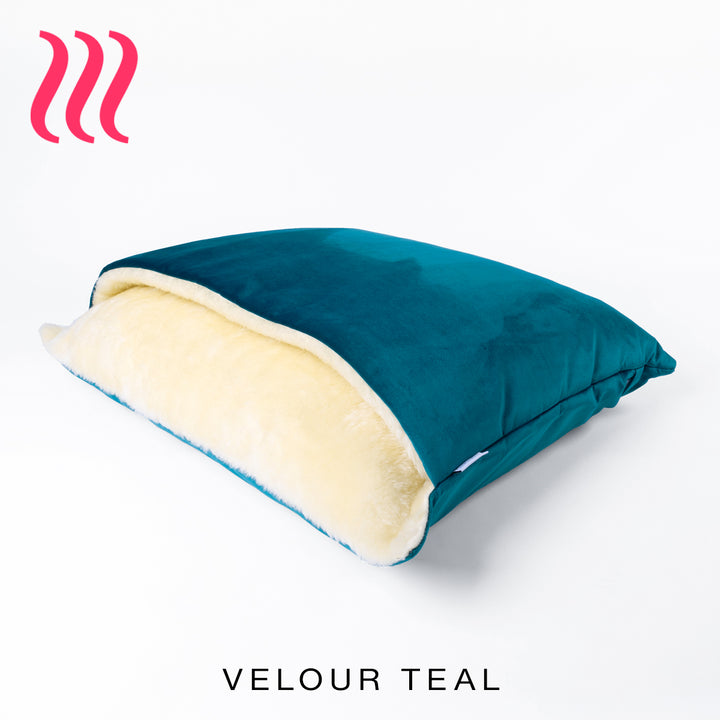 Luxury Dog Snuggle Bed, a sleeping bag style dog bed, with the outer cover in a bright teal green colour velvet and cream faux-fur on the inside of the bed, on a white background.