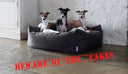 three dogs in a fark brown luxury dog bed with a white faux-fur blanket in a home setting with stone floor and whitewashed stone wall, with a "beware of the fakes" stamp on the imge to warn people of the risk of counterfeit goods.