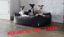 three dogs in a fark brown luxury dog bed with a white faux-fur blanket in a home setting with stone floor and whitewashed stone wall, with a "beware of the fakes" stamp on the imge to warn people of the risk of counterfeit goods.