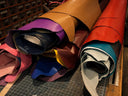 Rolled leather hides in various colours on a workbench ready to be cut into bespoke leather dog collars