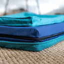 Close up detail shot of a luxury memeory foam dog bed mattress with the jade green outer cover unzipped showing a dark blue anti-microbial waterproof bed liner under the bed cover. 