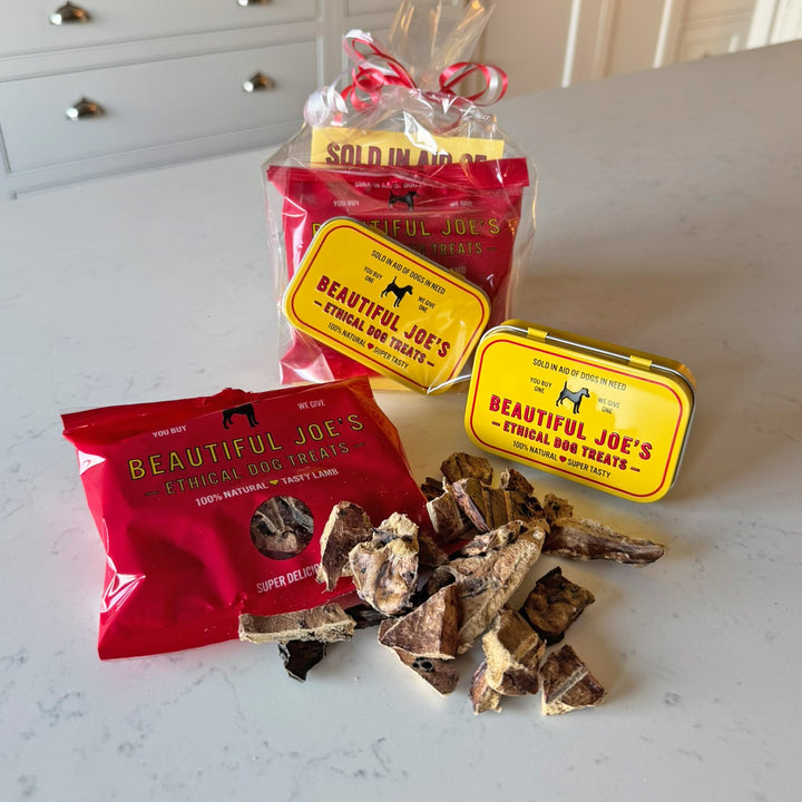 A gift bag of dog treats and a storage tin on a kitchen marble kitchen worktop 