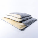 Three Charley Chau lxuury dog burrow bags stacked up in a pale grey polka dot fabric with a cream faux-fur lining on a white backdrop.