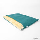 A jade green sleeping bag style dog bed, a luxury dog burrow bag by designers Charley Chau, with cream faux-fur fleece lining on a white backdrop.