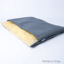 A grey colour luxury dog burrow bag, a snuggle sack style dog bed, by designers Charley Chau with a grey outer cover and cream faux-fur fleece lining on a white backdrop.