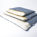 A stack of three luxury dog burrow bags by designers Charley Chau with grey outer covers and cream faux-fur fleece linings on a white backdrop.