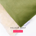 Close up of the corner of a luxury Dog Burrow Bag, a snuggle sack style dog bed or sleeping bag style dog bed, with a moss green upholstery-quality Velour outer cover and plush cream faux-fur lining, showing a Charley Chau designer brand label on the dog bed, on a white background.