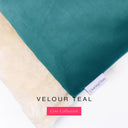 Close up of the corner of a luxury Dog Burrow Bag, a snuggle sack style dog bed or sleeping bag style dog bed, with a deep teal upholstery-quality Velour outer cover and plush cream faux-fur lining, showing a Charley Chau designer brand label on the dog bed, on a white background.