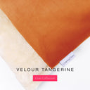 Close up of the corner of a luxury Dog Burrow Bag, a snuggle sack style dog bed or sleeping bag style dog bed, with a bright orange upholstery-quality Velour outer cover and plush cream faux-fur lining, showing a Charley Chau designer brand label on the dog bed, on a white background.