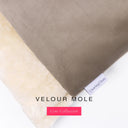 Close up of the corner of a luxury Dog Burrow Bag, a snuggle sack style dog bed or sleeping bag style dog bed, with a warm taupe grey upholstery-quality Velour outer cover and plush cream faux-fur lining, showing a Charley Chau designer brand label on the dog bed, on a white background.