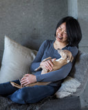 Christine Chau of Charley Chau holding an Italian Greyhound dog in her lap and laughing.