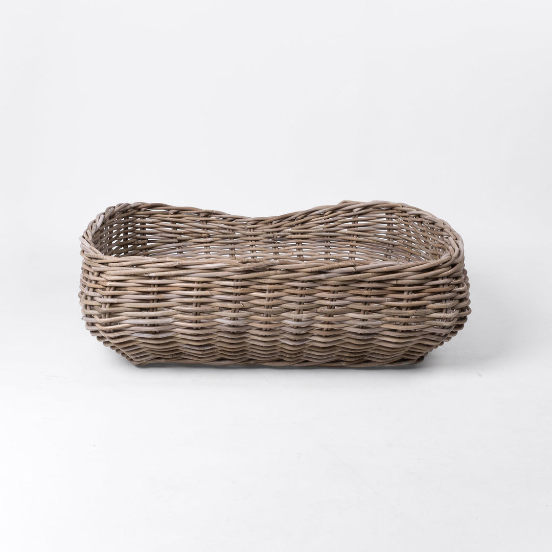 A classic wicker dog basket - a grewash rattan dog basket - woven with natural rattan canes, on a white background, viewed from the back.