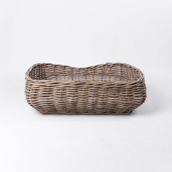 A classic wicker dog basket - a grewash rattan dog basket - woven with natural rattan canes, on a white background, viewed from the back.