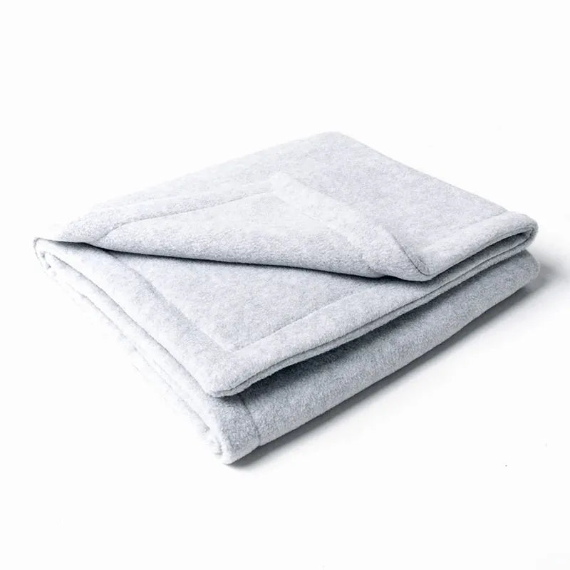 Folded pale grey fleece dog blanket for warm weatheron a white background