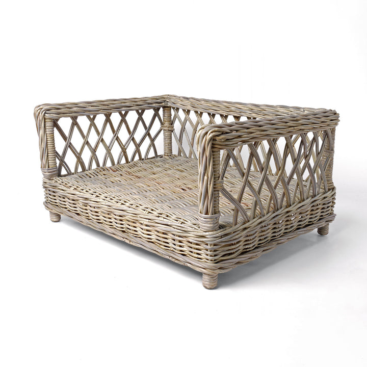 Raised Rattan Dog Bed frame on a white background. A raised dog bed woven with rattan canes to create a lattice style frame.