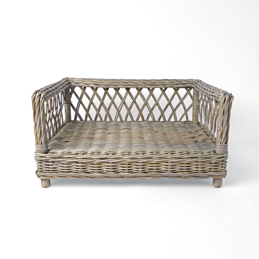 Raised Rattan Dog Bed frame on a white background. A raised dog bed woven with rattan canes to create a lattice style frame.