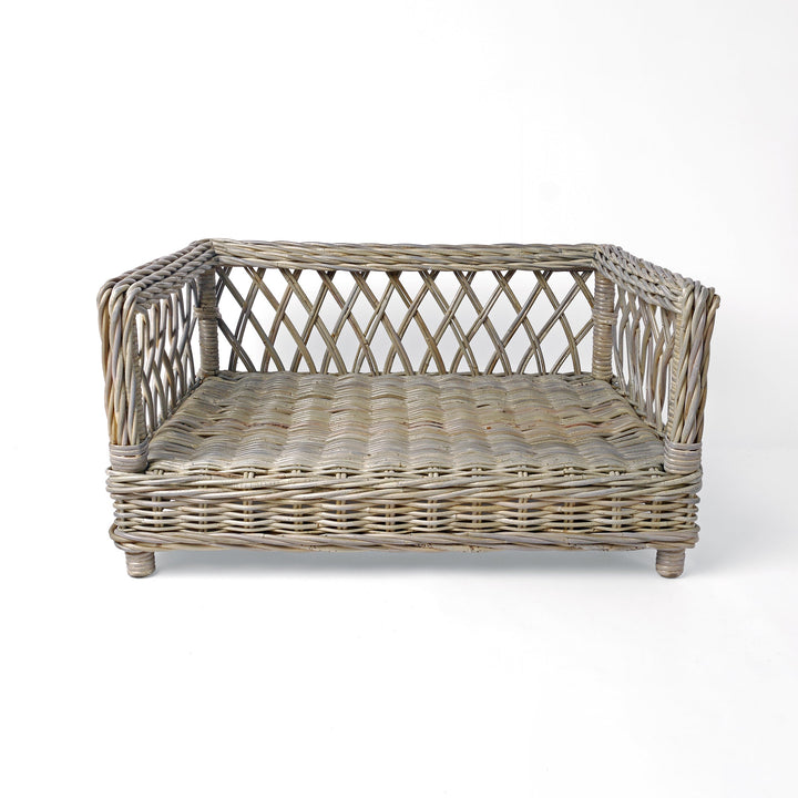Raised Rattan Dog Bed frame on a white background. A raised dog bed woven with rattan canes to create a lattice style frame.