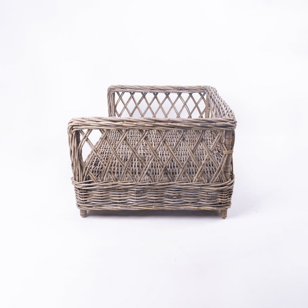 Side view of Charley Chau's Raised Rattan Dog Bed frame, woven with natural rattan canes with a lattice effect, placed on a white background.