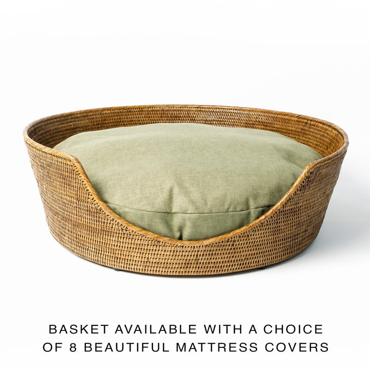 A golden tan colour round Rattan Dog Basket with a fern green dog bed mattress inside with text advising of multiple colour choices available for the dog bed mattress.