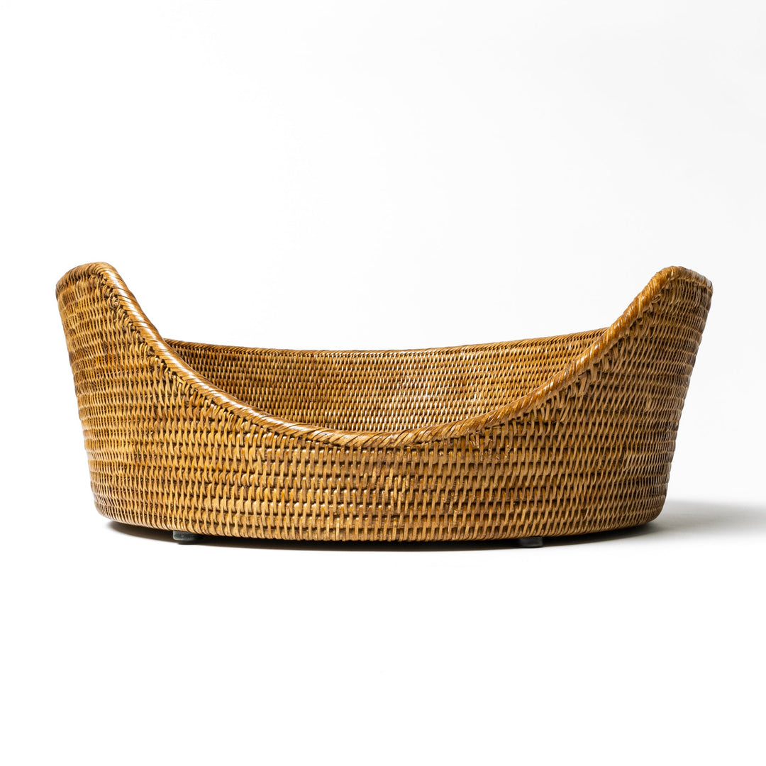 An close up shot of the front of a  tan beige coloured round rattan dog basket on a white background.