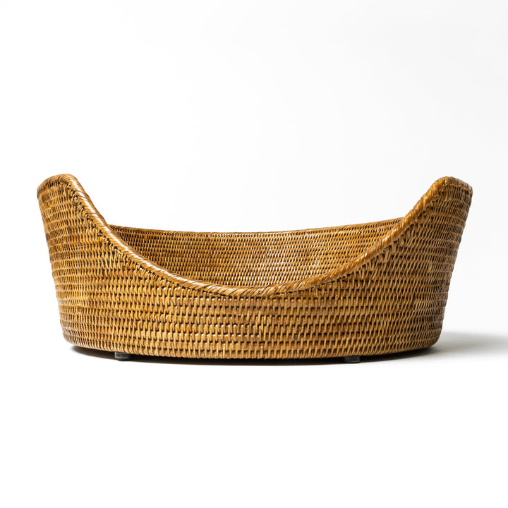 An close up shot of the front of a  tan beige coloured round rattan dog basket on a white background.