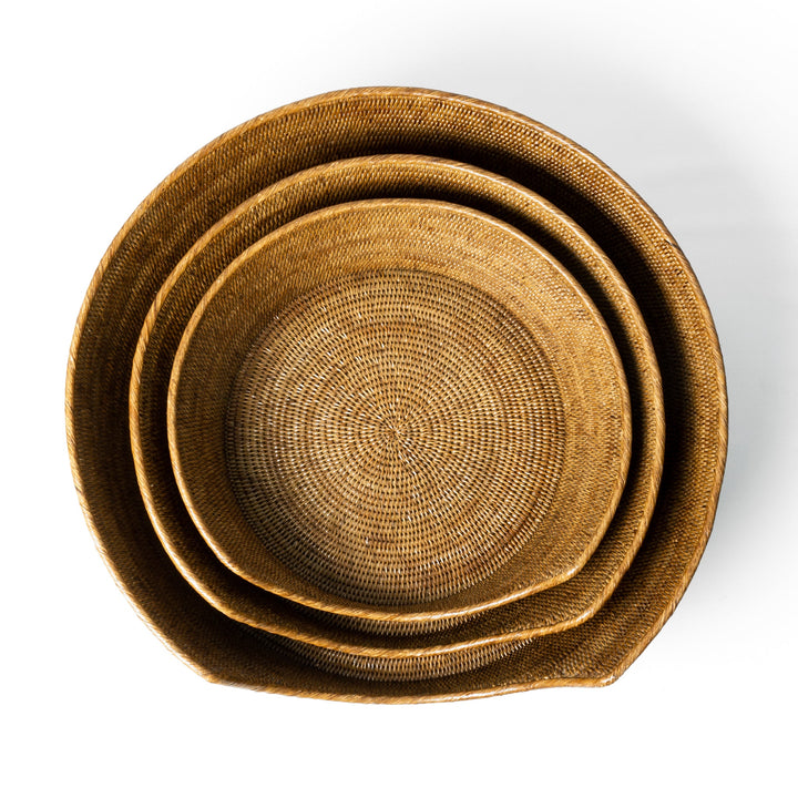 An overhead shot looking down onto three round golden tan coloured rattan peel dog baskets nested together. 