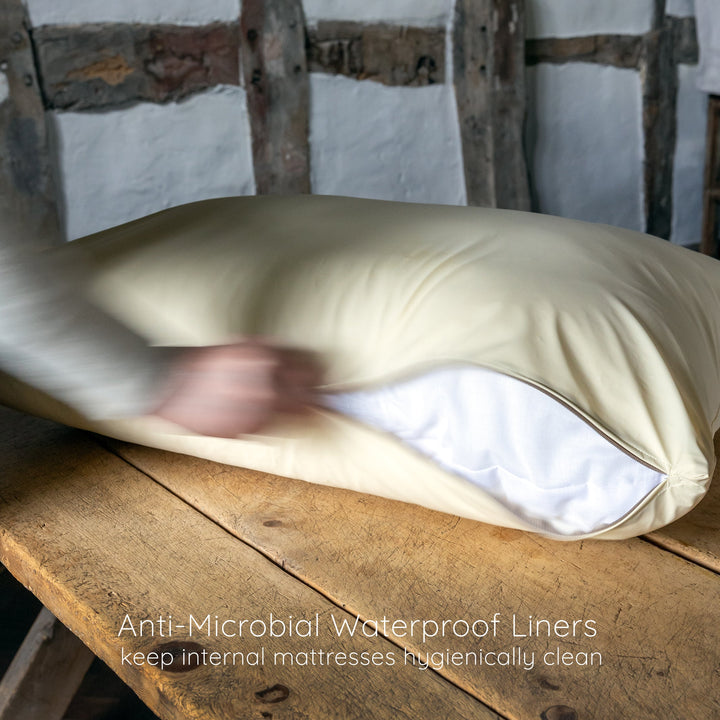 A person unzipping a an anti-bacterial waterproof bed liner cover from a deep-filled Dog Bed Mattress on a wooden table.