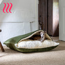 Dog peeking out from a sleeping bag style luxury Snuggle Dog Bed in leaf  green velvet with a white interior on a hessian carpeted floor. 