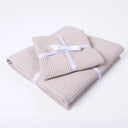 A set of folded pale beige waffle texture cotton dog blankets folded and individually tied with a white ribbon and bow on a clean white background.