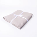 A folded pale beige waffle texture cotton dog blanket, tied with a white ribbon bow, on a clean white background.