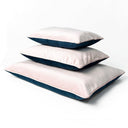 Three rectangular dog bed mattresses, Day Beds, in navy and pale pink stacked on top of each other on a white background.