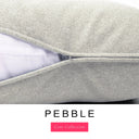 Close-up of a light beige-grey  woven dog bed mattress with a removable cover partially unzipped revealing a deep-filled luxury dog bed mattress inside, above a white banner with the text 'PEBBLE' and 'Core Collection'.