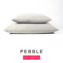 Two luxury machine washable dog bed mattresses in a light beige-grey upholstery fabric stacked on top of each other with 'PEBBLE' and a pink 'Core Collection' label on a white background. 
