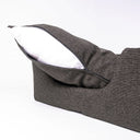 Close up of the matttress of a dark brown high-sided luxury dog bed, withthe mattress lifted up slightly and unzipped to show the internal deep-filled dog bed mattresson a white backdrop.