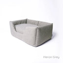 Grey high-sided luxury dog bed made with a textured woven upholstery fabric on a white backdrop.