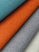 Close-up of upholstery quality soft-furnighsings fabric swatches in jade green, orange, gray, and beige.