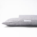 Close up detail of the corner of a luxury dog burrow bag by designers Charley Chau, a sleeping bag style dog bed with a built in cover, in a woven grey upholstery fabric on a white background