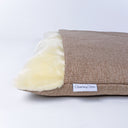 Detail of a luxury Dog Burrow Bag with a hard-wearing beige woven upholstery fabric outer cover and plush cream faux-fur lining and Charley Chau designer brand label on a white backdrop.
