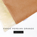 A close up detail of the corner of a Charley Chau Burrow Bag Dog Bed with terracotta orange outer cover in woven wool texture upholstery fabric Faroe and plush cream faux-fur lining with a woven brand label showing the Charley Chau logo on a white backdrop.
