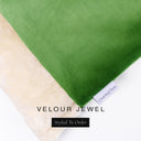 A close up detail of the corner of a Charley Chau Burrow Bag Dog Bed with emerald green outer cover in upholstery-quality Velour and plush cream faux-fur lining with a woven brand label showing the Charley Chau logo on a white backdrop.