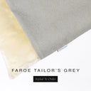 A close up detail of the corner of a Charley Chau Burrow Bag Dog Bed with light grey outer cover in woven wool texture upholstery fabric Faroe and plush cream faux-fur lining with a woven brand label showing the Charley Chau logo on a white backdrop.