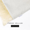 A close up detail of the corner of a Charley Chau Burrow Bag Dog Bed with pale cream outer cover in woven wool texture upholstery fabric Faroe and plush cream faux-fur lining with a woven brand label showing the Charley Chau logo on a white backdrop.