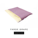 A luxurious Dog Burrow Bag, a sleeping bag style dog bed or snuggle sack style dog bed, with an outer cover in dusty mauve woven wool texture upholstery fabric Faroe with a plush, cream faux-fur lining, and a badge with the colour name Grape on a white background.