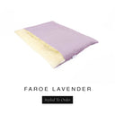 A luxurious Dog Burrow Bag, a sleeping bag style dog bed or snuggle sack style dog bed, with an outer cover in pale lilac woven wool texture upholstery fabric Faroe with a plush, cream faux-fur lining, and a badge with the colour name Lavender on a white background.