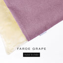 A close up detail of the corner of a Charley Chau Burrow Bag Dog Bed with dusty mauve outer cover in woven wool texture upholstery fabric Faroe and plush cream faux-fur lining with a woven brand label showing the Charley Chau logo on a white backdrop.
